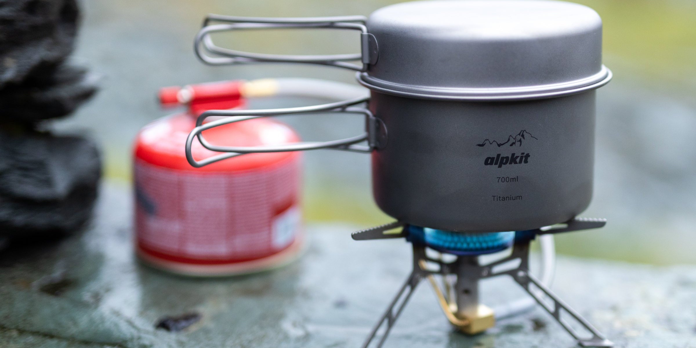 Lightweight camping stove boiling water on a stone wall