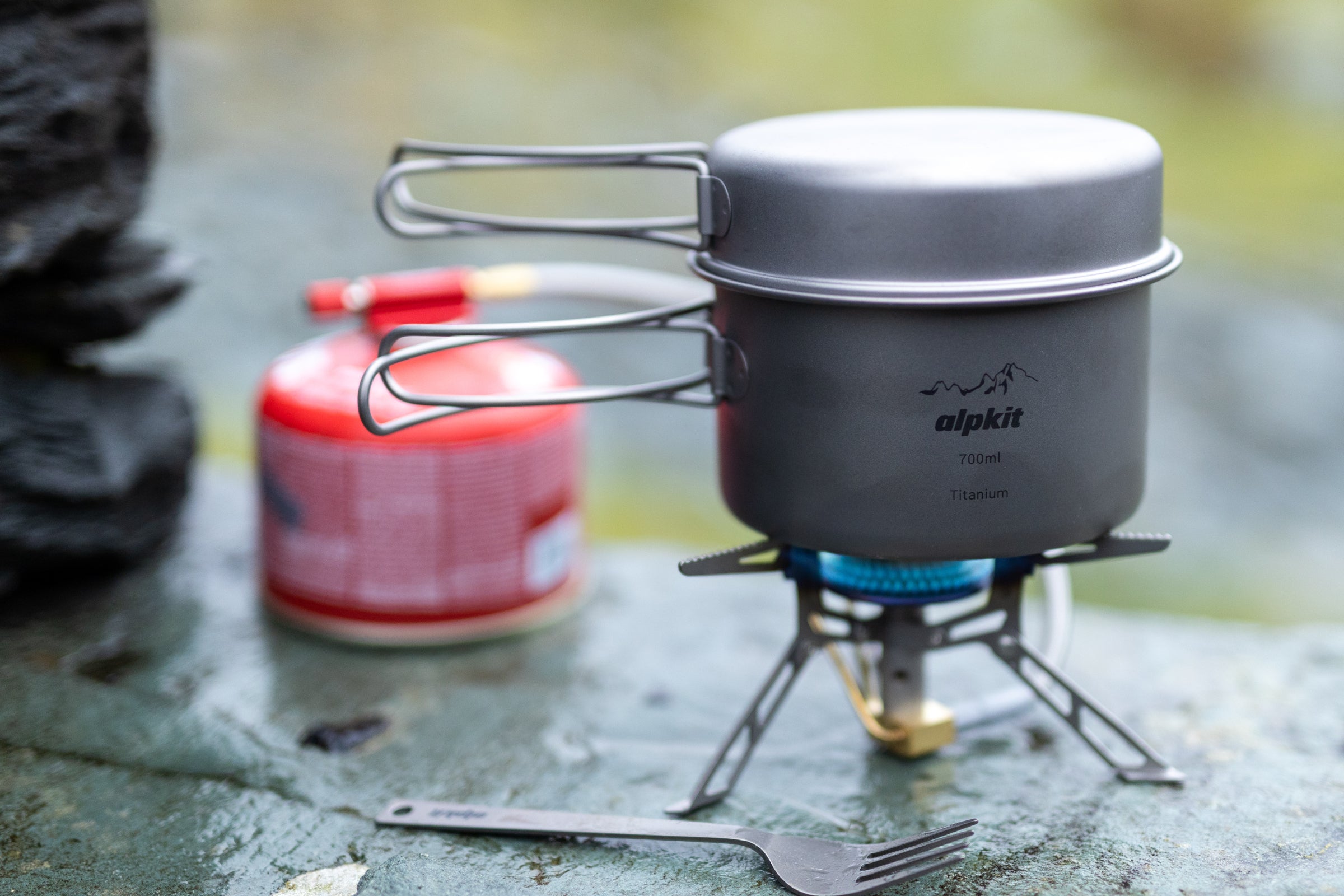 Lightweight camping stove boiling water on a stone wall