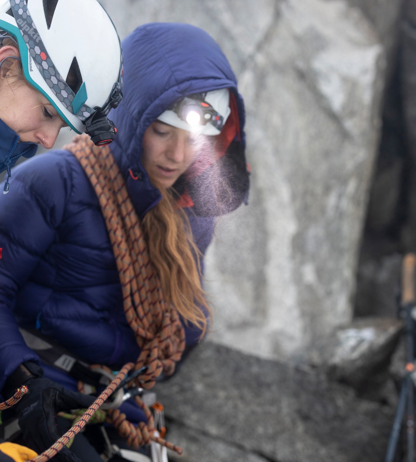 Two winter climbers wearing head torches on a belay
