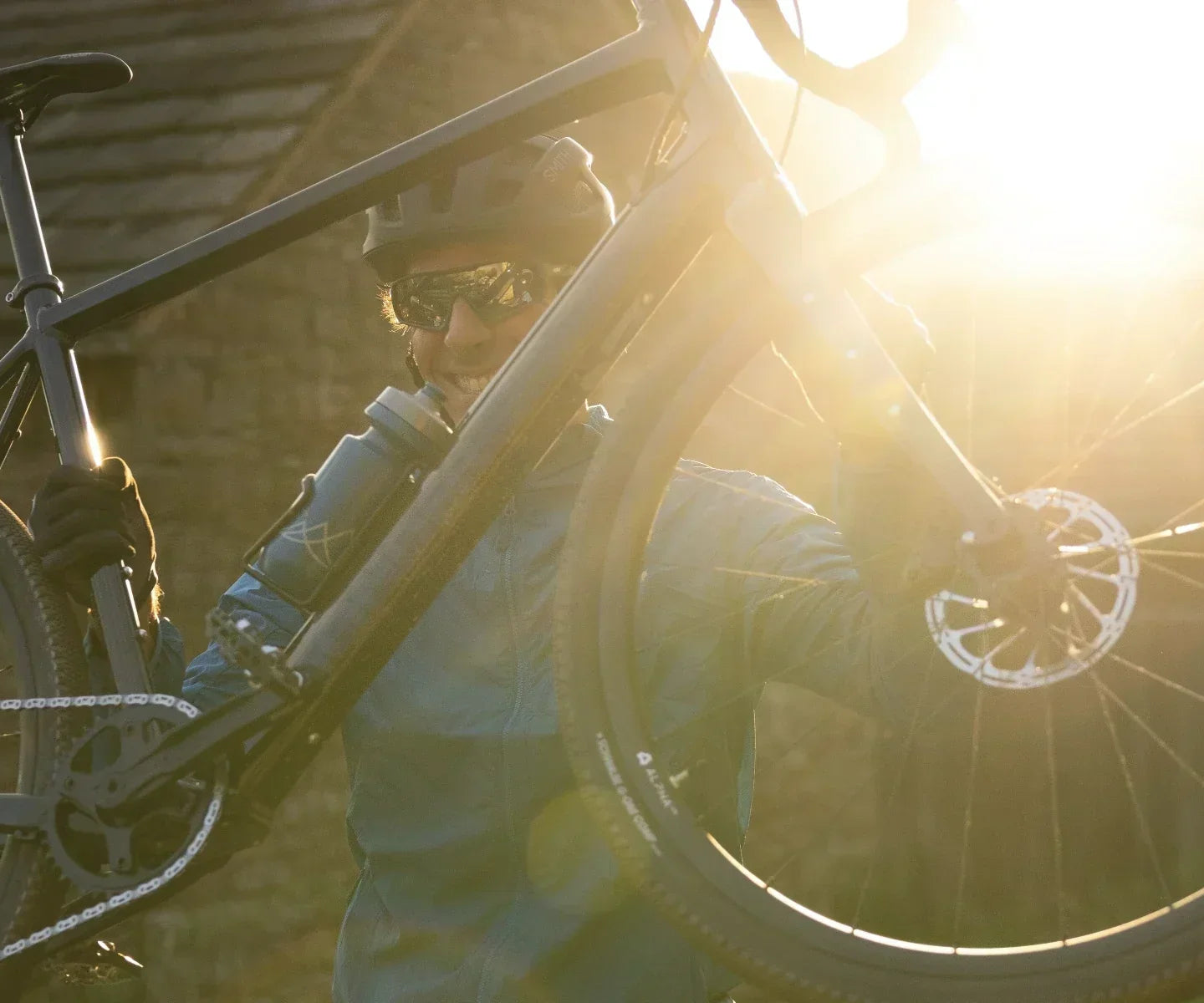 Rider lifting a lightweight e-gravel bike over a gate
