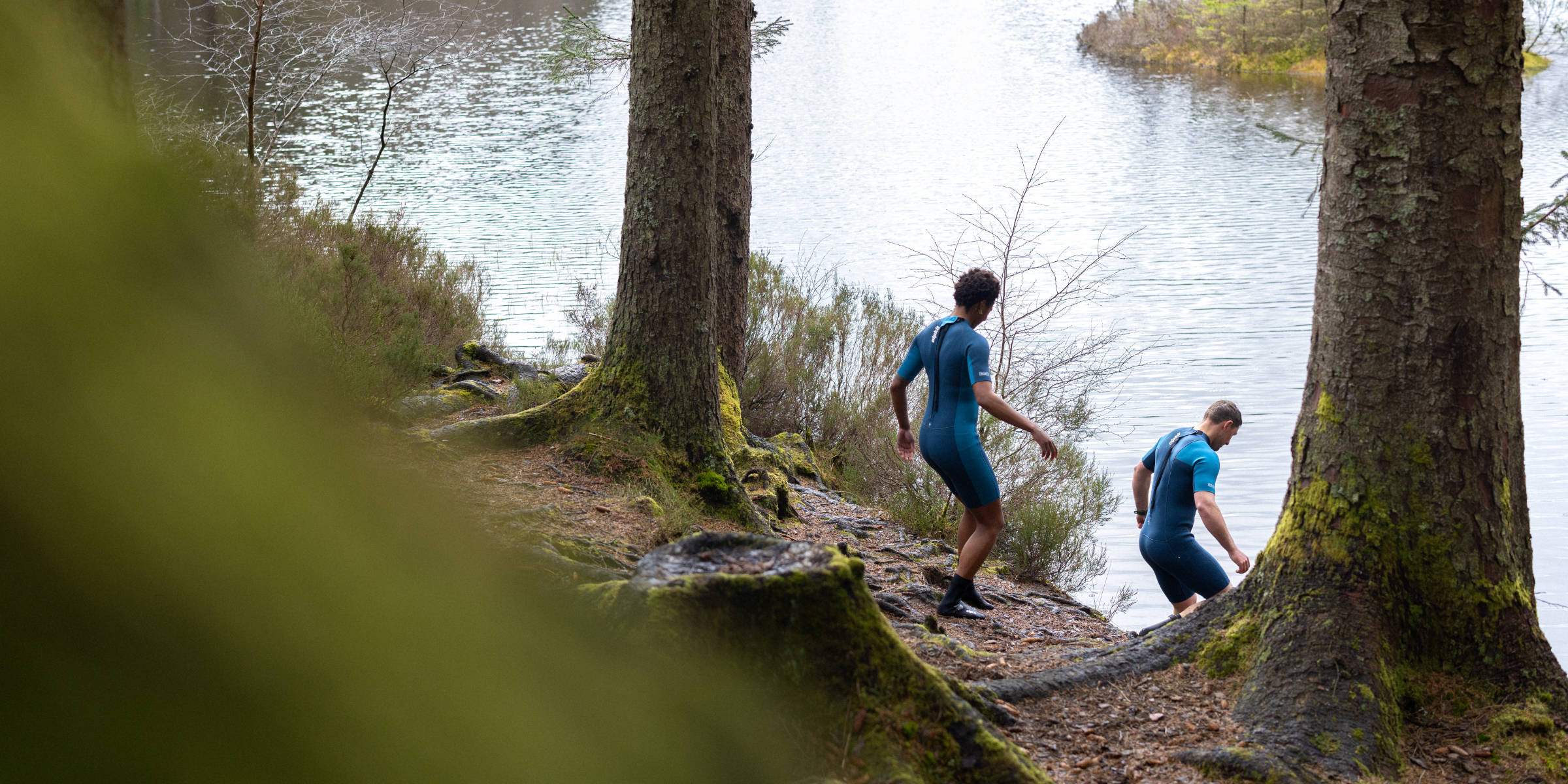 Outdoor swimmers entering the water in wetsuits