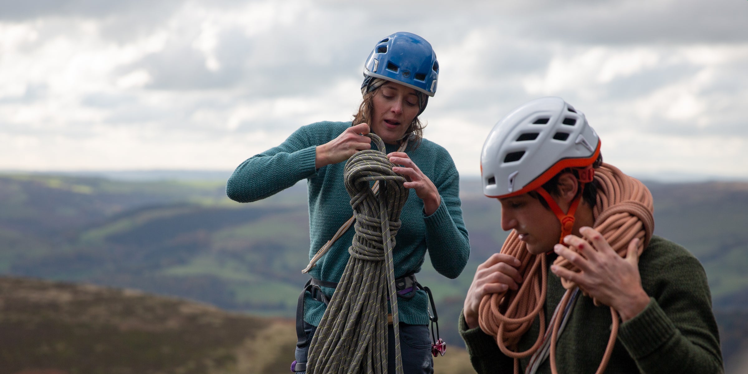 A man and a woman climbing in wool jumpers on Stanage Edge in the Peak District