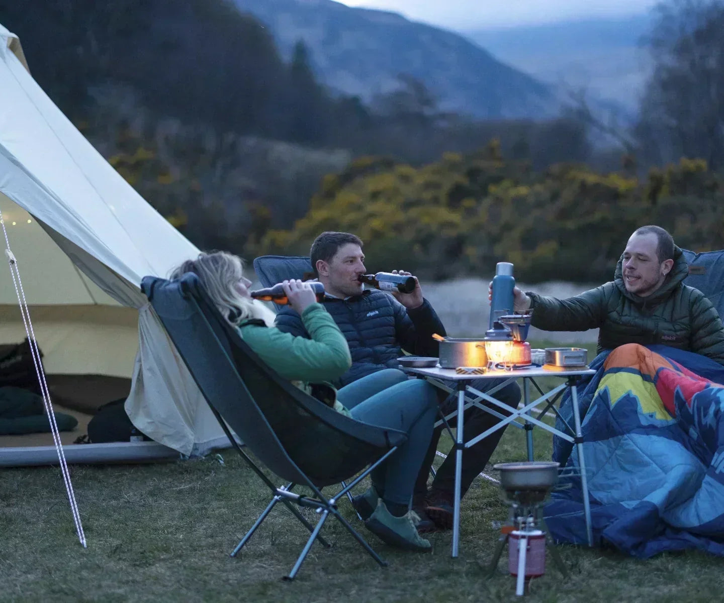 Campers staying warm outside a tent under blankets