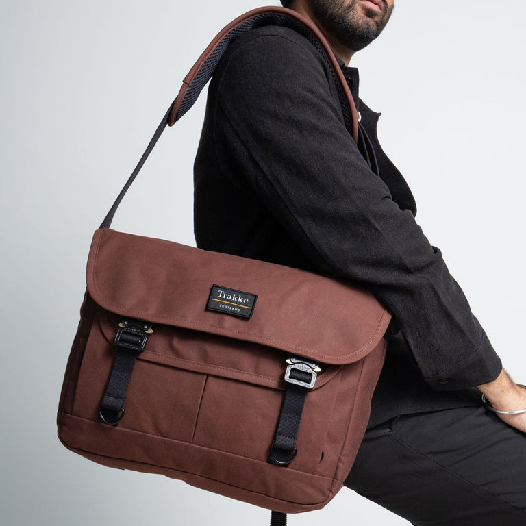 a man sitting on a stool with the bairn pro messenger in port colour