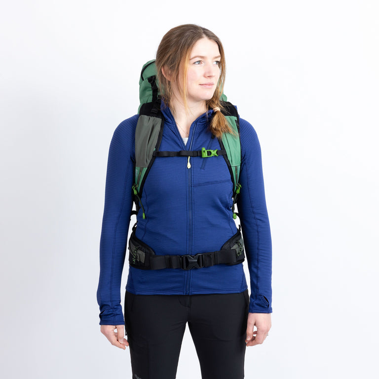 Person wearing a blue jacket and green backpack on a white background