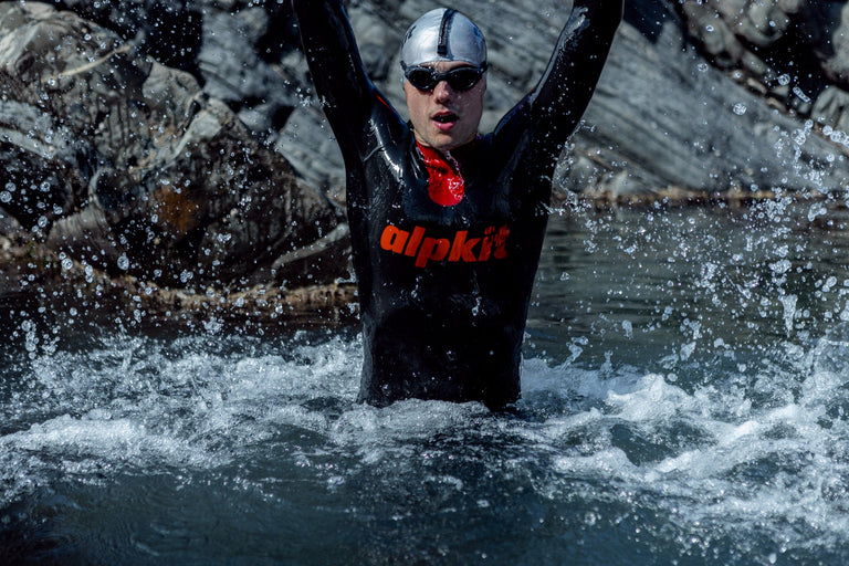 A man jumping up through the water in an outdoor swimming wetsuit - action