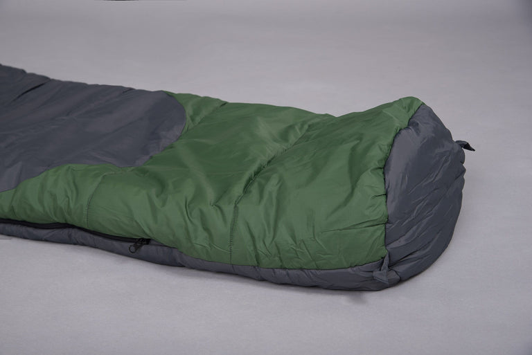 The foot end of a Mountain Ghost 200 synthetic 2 season sleeping bag in green and grey laid on the floor on a grey background