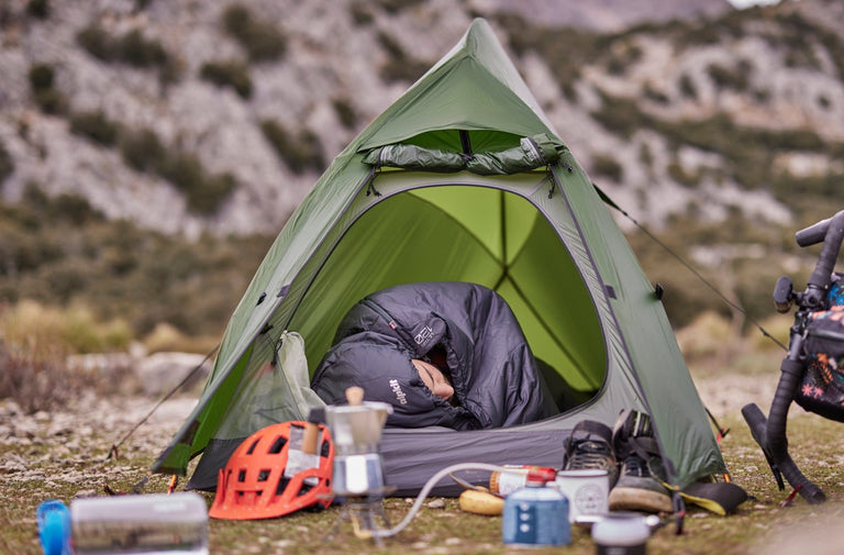 A man sleeping in a bikepacking tent in an ultralight PrimaLoft® sleeping bag - action