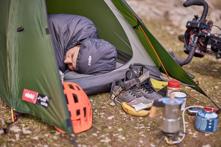 A man sleeping in a bikepacking tent in an ultralight PrimaLoft® sleeping bag - action - closed