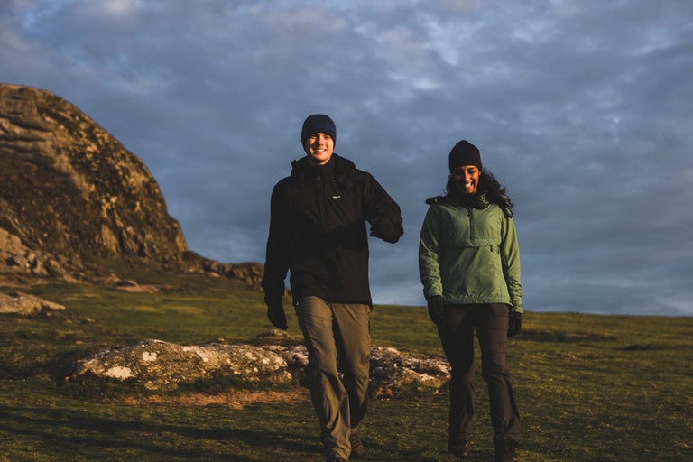 A man and a woman walking in black and green Jura Mountain Smocks - action - closed