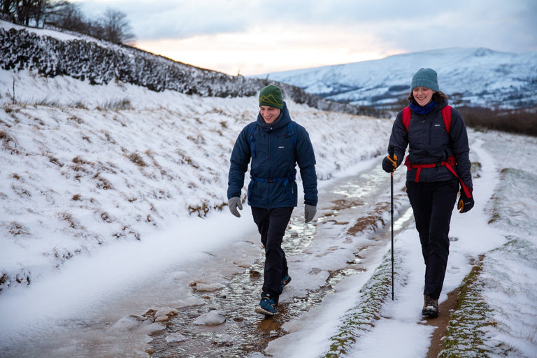 A man and a woman hiking along a lane in the snowy Peak District - action