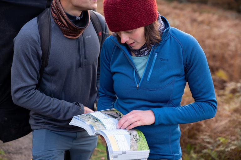 A man and a woman looking at a climbing guide book wearing fleeces - action