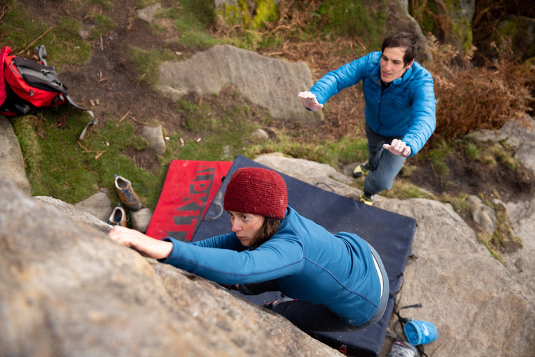 A woman bouldering in a stretchy blue fleece - action