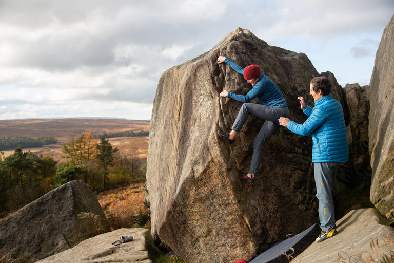 A woman bouldering in a stretchy blue fleece - action